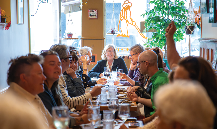 Friends sharing a long table at a busy Oneonta restaurant